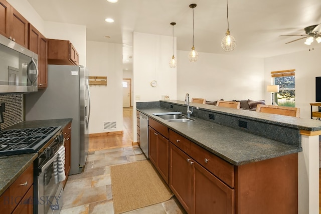 kitchen featuring appliances with stainless steel finishes, a breakfast bar, pendant lighting, ceiling fan, and sink