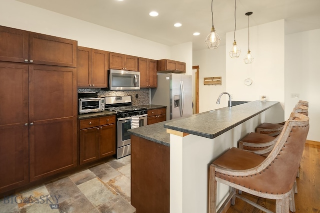 kitchen featuring stainless steel appliances, hanging light fixtures, kitchen peninsula, and a breakfast bar