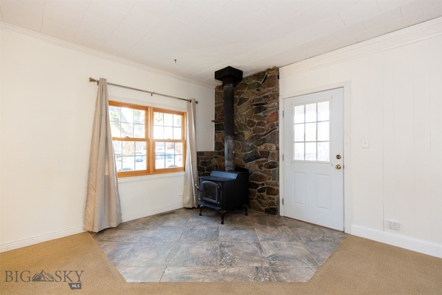 foyer entrance featuring carpet, ornamental molding, and a wood stove