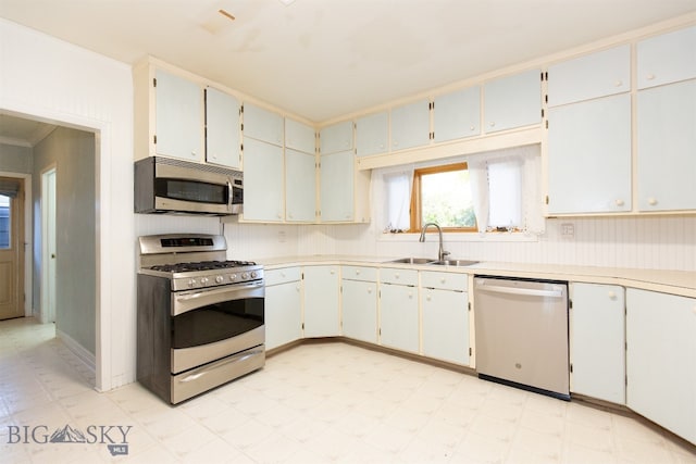 kitchen with ornamental molding, stainless steel appliances, white cabinets, and sink