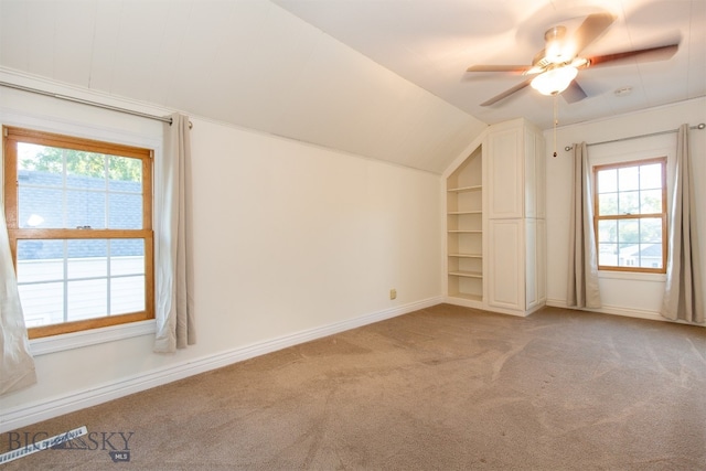 additional living space featuring light carpet, ceiling fan, vaulted ceiling, and a healthy amount of sunlight