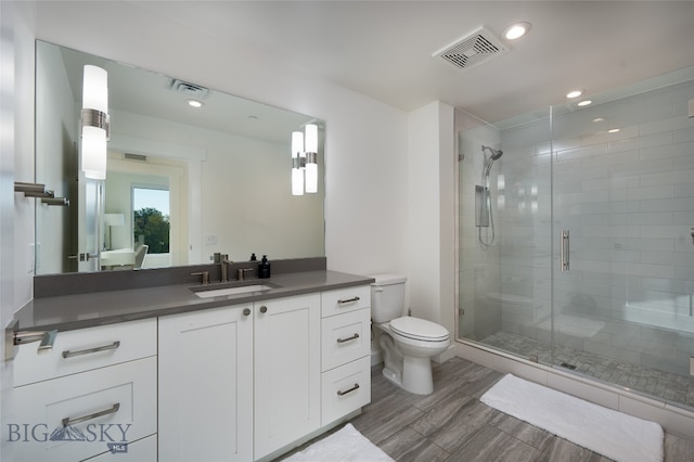 bathroom with vanity, toilet, and a shower with door