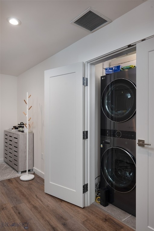 laundry area featuring stacked washer / drying machine and hardwood / wood-style floors