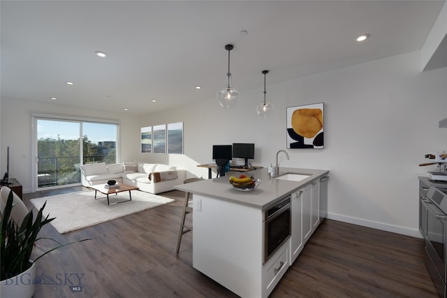 kitchen with a breakfast bar, sink, white cabinetry, kitchen peninsula, and dark hardwood / wood-style flooring