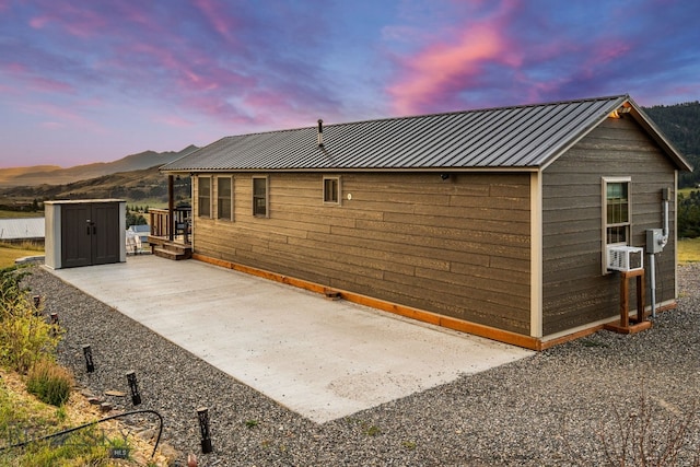 back house at dusk with a storage unit, a mountain view, and a patio area