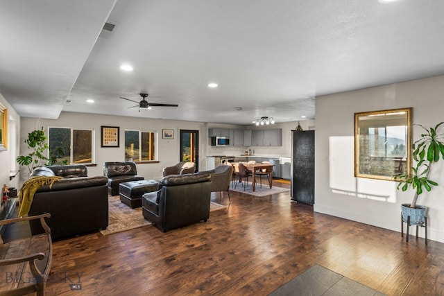 living room featuring ceiling fan and dark hardwood / wood-style floors