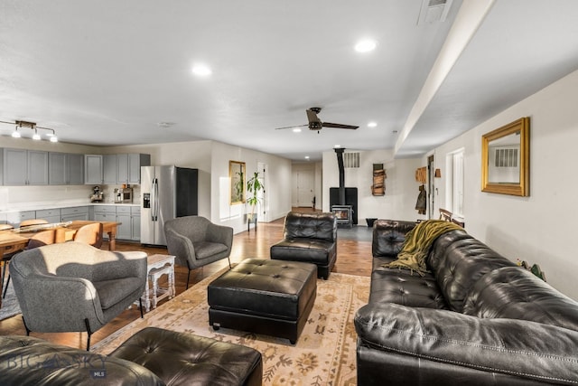 living room featuring a wood stove, light hardwood / wood-style floors, and ceiling fan