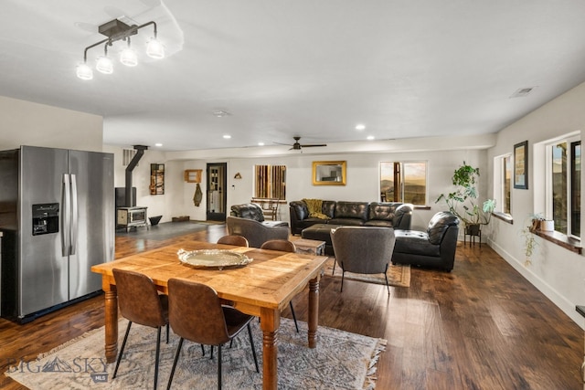 dining area featuring dark hardwood / wood-style flooring, ceiling fan, and a wood stove