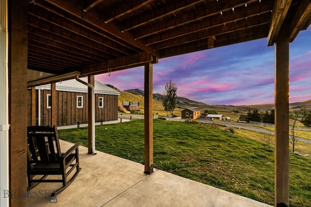 31 Bull Run Rd, Livingston, MT 59047 - patio terrace at dusk featuring a storage shed, a lawn, an outdoor structure, and a mountain view