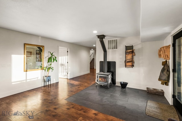 interior space featuring dark wood-type flooring, a wood stove, and a wealth of natural light