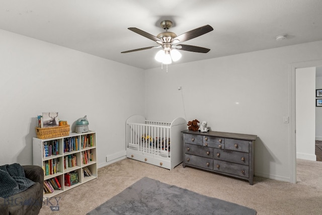 carpeted bedroom with ceiling fan and a crib