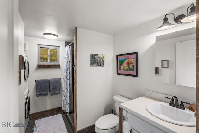 bathroom featuring stacked washer / drying machine, vanity, and toilet