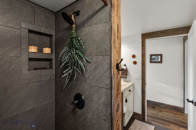 bathroom with a tile shower, vanity, and hardwood / wood-style floors