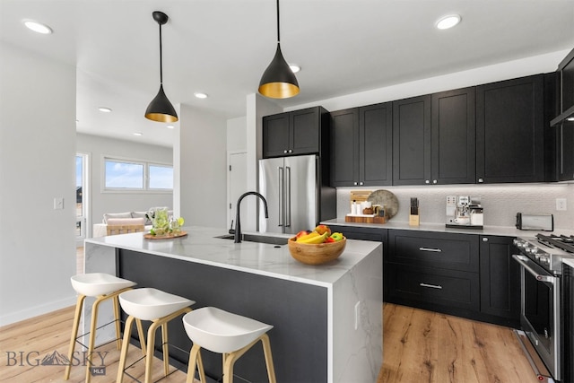 kitchen featuring light hardwood / wood-style floors, tasteful backsplash, sink, a center island with sink, and high quality appliances