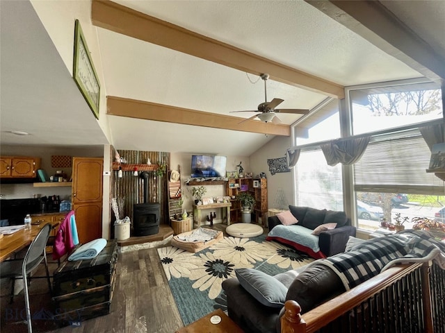 living room with wood-type flooring, lofted ceiling with beams, a wood stove, and ceiling fan