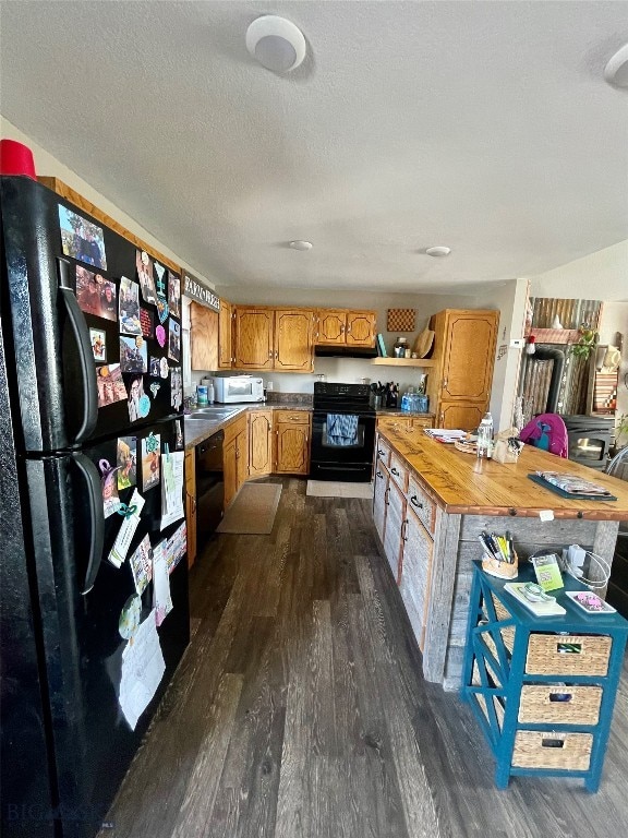 kitchen with butcher block countertops, a textured ceiling, dark hardwood / wood-style floors, and black appliances