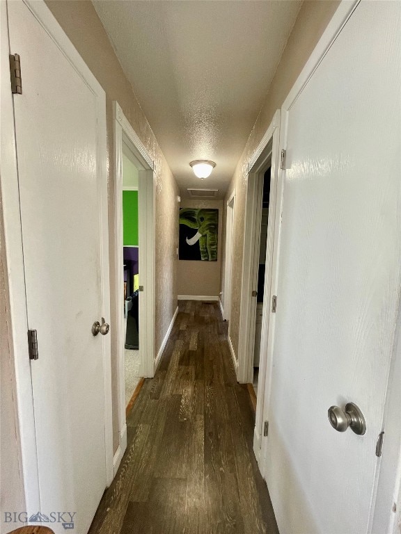 hallway with a textured ceiling and dark wood-type flooring