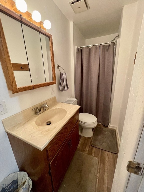 bathroom with vanity, hardwood / wood-style flooring, walk in shower, and toilet