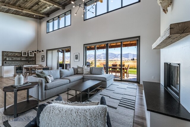 living room with wood ceiling, hardwood / wood-style floors, an inviting chandelier, a towering ceiling, and a mountain view