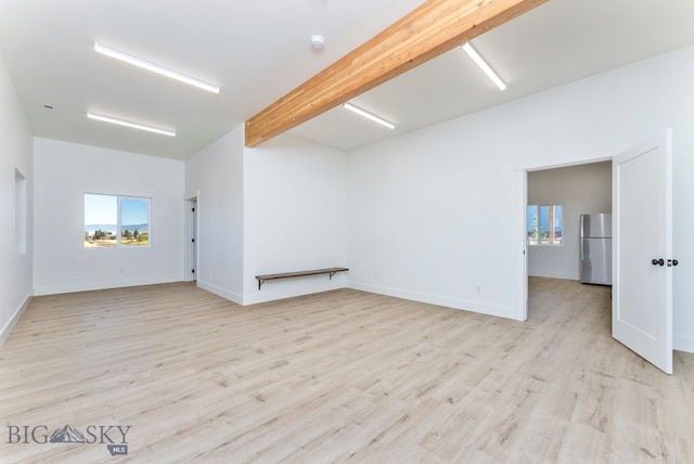 empty room featuring light hardwood / wood-style flooring and beam ceiling