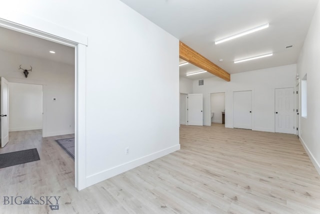 spare room featuring beamed ceiling and light wood-type flooring