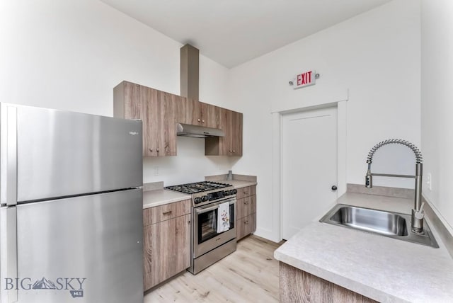 500 Stubbs Ln, Bozeman, MT 59718 - kitchen featuring appliances with stainless steel finishes, under cabinet range hood, light wood-style floors, light countertops, and brown cabinets