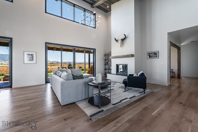 living room with a towering ceiling, hardwood / wood-style floors, beamed ceiling, and a wealth of natural light