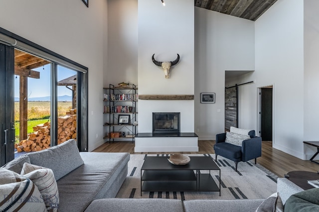 living room featuring hardwood / wood-style floors, a barn door, wood ceiling, and high vaulted ceiling