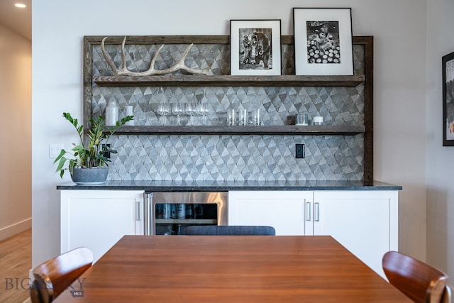 bar with white cabinetry, hardwood / wood-style flooring, tasteful backsplash, and beverage cooler