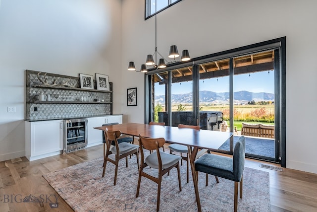 dining space featuring a mountain view, wine cooler, light wood-type flooring, and plenty of natural light