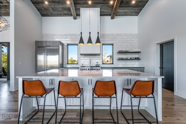 kitchen featuring a spacious island, dark wood-type flooring, a kitchen breakfast bar, and built in refrigerator