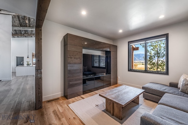 living room featuring beamed ceiling and light hardwood / wood-style flooring