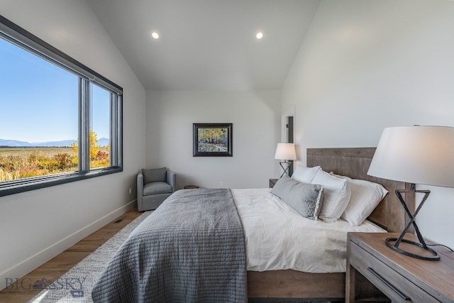 bedroom featuring vaulted ceiling, a mountain view, and hardwood / wood-style flooring