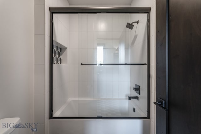 bathroom featuring shower / bath combination with glass door and toilet