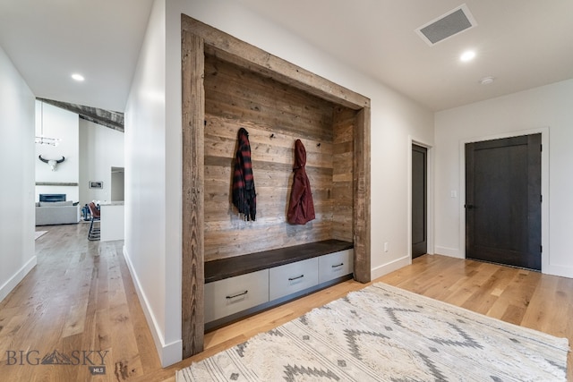 mudroom with hardwood / wood-style floors and a fireplace