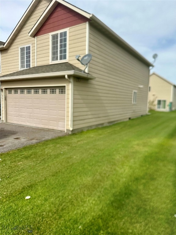 view of side of home featuring a lawn and a garage