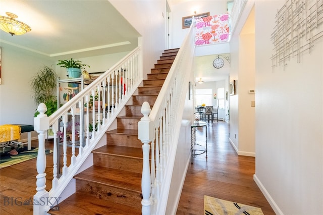 staircase with crown molding and hardwood / wood-style floors