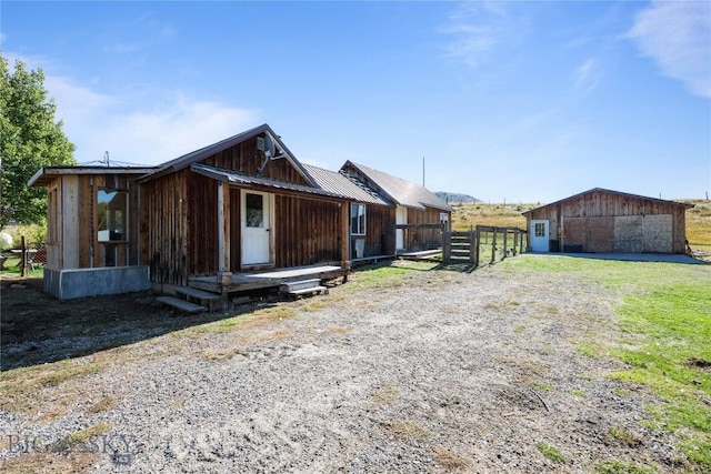 exterior space with fence, an outbuilding, and metal roof