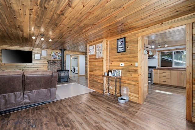 living room with wood ceiling, wooden walls, hardwood / wood-style floors, and a wood stove