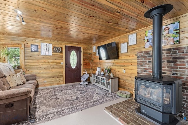 living area with wooden walls, a wood stove, and wooden ceiling