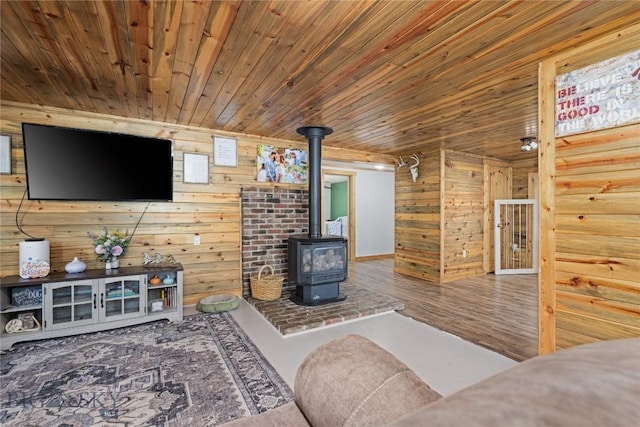 living area featuring wood walls, wood finished floors, a wood stove, and wooden ceiling