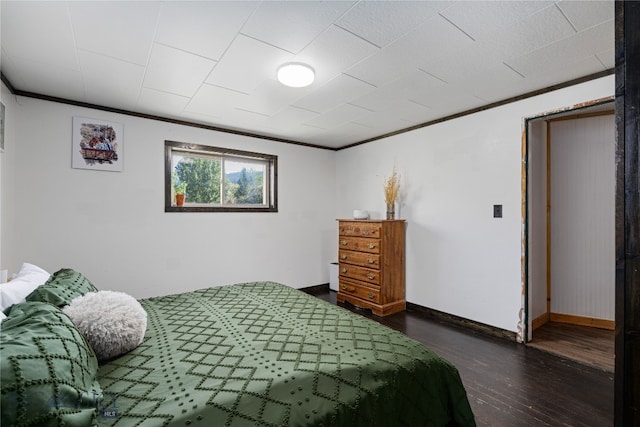 bedroom with a barn door, crown molding, and dark hardwood / wood-style flooring