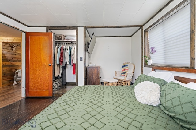 bedroom with a closet, wooden walls, and dark wood-type flooring