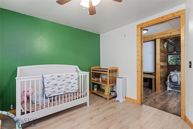 bedroom featuring baseboards, wood finished floors, and a ceiling fan