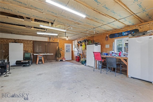 garage featuring a workshop area, refrigerator, and freestanding refrigerator