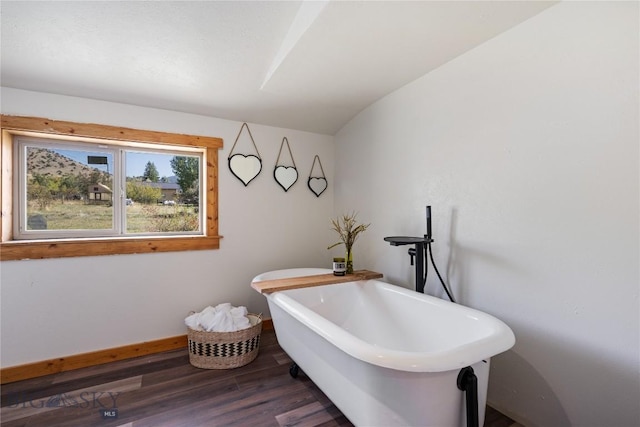 miscellaneous room featuring baseboards, wood finished floors, and lofted ceiling
