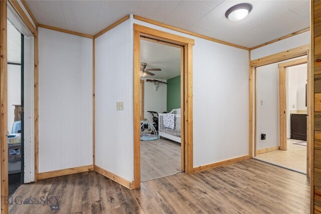 interior space featuring wood finished floors, a closet, wood walls, ornamental molding, and baseboards