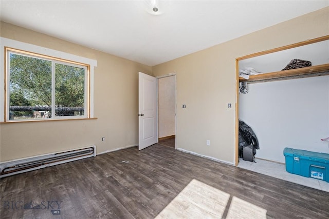 unfurnished bedroom featuring baseboard heating, baseboards, wood finished floors, and a closet
