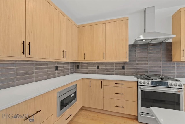 kitchen with wall chimney exhaust hood, stainless steel appliances, and light brown cabinetry