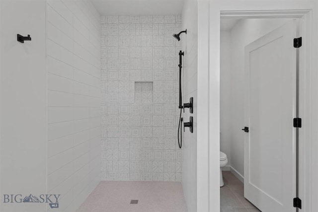 bathroom with a tile shower, tile patterned floors, and toilet